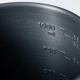 Close-up of a dark gray brushed metal pot or container showing embossed volume markings including 1000 ml, 750, and 500.