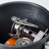 Close-up of a dark gray 1000 ml camping pot containing a portable gas stove and an orange fuel canister.